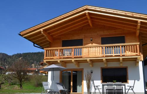 a house with a deck with chairs and an umbrella at Chalet Groissenbach in Reit im Winkl