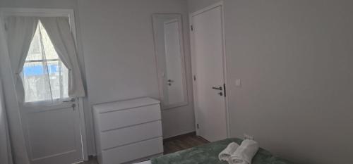 a white bedroom with a bed and a window at Machico Heart Suites in Machico