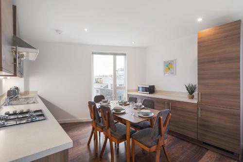 a kitchen with a table and chairs in a kitchen at Modern & spacious 3 bed with free parking & lift in Shoreditch, next to station in London