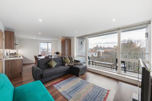 a living room with a couch and a large window at Modern & spacious 3 bed with free parking & lift in Shoreditch, next to station in London