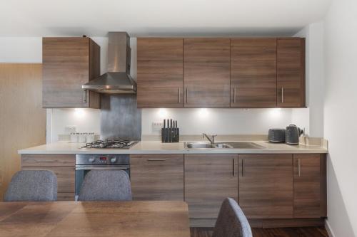 a kitchen with wooden cabinets and a sink at Modern & spacious 3 bed with free parking & lift in Shoreditch, next to station in London