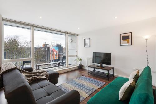a living room with a couch and a large window at Modern & spacious 3 bed with free parking & lift in Shoreditch, next to station in London
