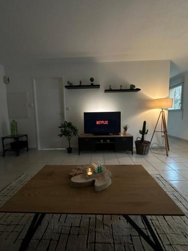 un salon avec une télévision et une table avec une bougie dans l'établissement Appartement entièrement rénové, à Roye