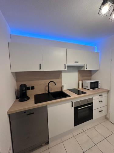 a kitchen with white cabinets and a sink and a microwave at Appartement de Charles in Roye
