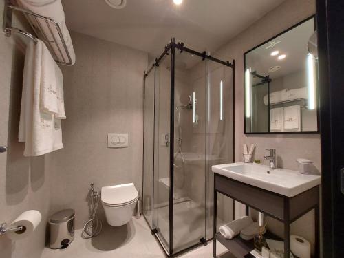a bathroom with a shower and a toilet and a sink at Mulaj Hotel in Tirana
