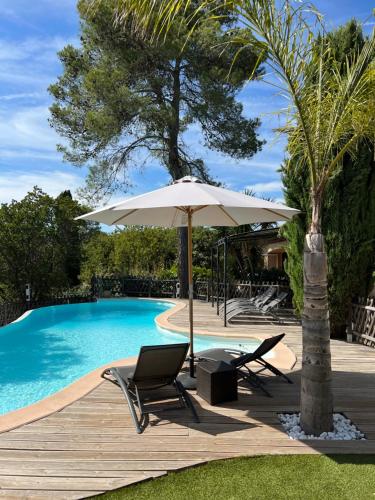 - une piscine avec 2 chaises, un parasol, une table et des chaises dans l'établissement Séjours à partir de 3 nuitées villa avec piscine à débordement, Spa et Pool house, à Bagnols-en-Forêt