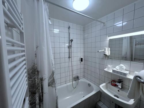 a bathroom with a shower and a tub and a sink at Brauereigasthof zur Münz seit 1586 in Günzburg