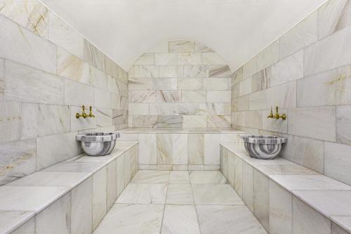 2 wastafels in een badkamer met marmeren muren bij Ramada by Wyndham Cesme in Çeşme