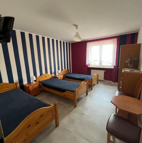a room with three beds and a striped wall at Podlaski Bon Turystyczny eMKa Noclegi apartamenty in Augustów