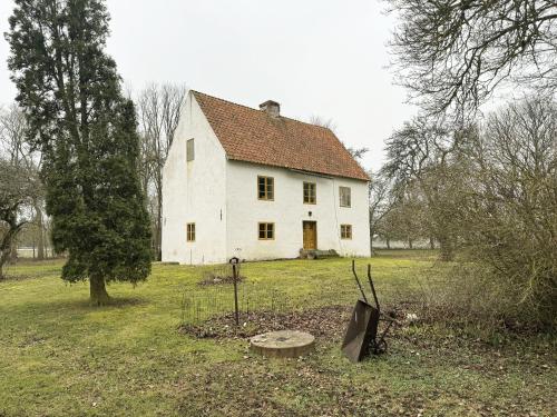 an old white house in the middle of a field at Genuine Gotland house with large garden in Roma in Romakloster