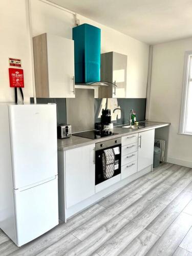 a kitchen with white cabinets and a white refrigerator at Luton flat with parking in Luton