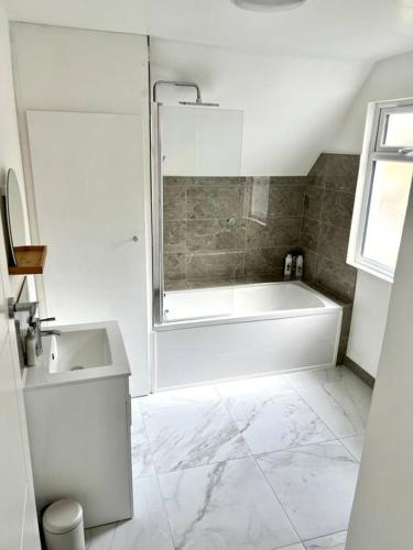 a white bathroom with a tub and a sink at Luton flat with parking in Luton