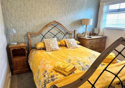 a bedroom with a bed with yellow sheets and pillows at Gilfach Ceidio in Morfa Nefyn