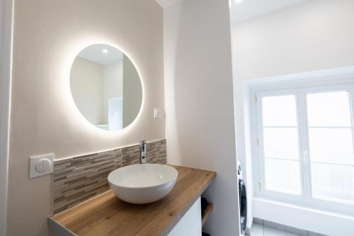 La salle de bains est pourvue d'un lavabo blanc et d'un miroir. dans l'établissement Très Bel Appartement Cosy et Central, à Cholet