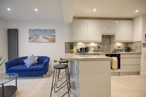 eine Küche und ein Wohnzimmer mit einem blauen Sofa in der Unterkunft Modern 5 Bedroom Fully upgraded with Free Parking in Earlham