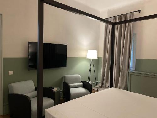 een slaapkamer met een bed en een tv en 2 stoelen bij Stunning Athens Apartment | 1 Bedroom | Apartment Juvia | Athinaidos in Athene