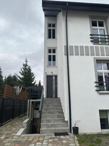 a white house with stairs leading up to the door at Apartamenty Bezrzecze in Szczecin