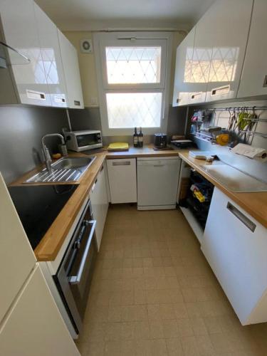 une cuisine avec des armoires blanches et un réfrigérateur blanc dans l'établissement 3 Pièces avec grande terrasse, à Cannes