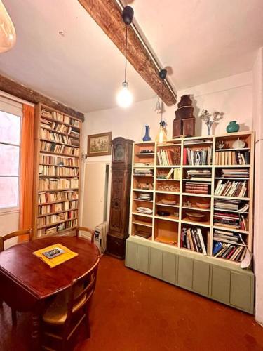 a room with a table and a book shelf with books at Abbaye - Appartement spacieux au coeur du Vieux-Nice in Nice