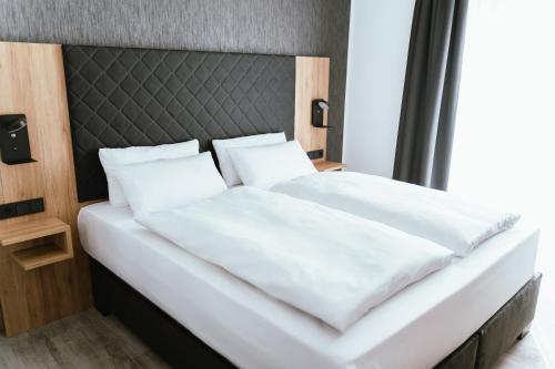 Cama blanca con cabecero negro y almohadas blancas en Hotel am Park Bad Driburg, en Bad Driburg