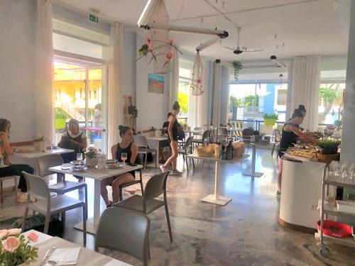 un groupe de personnes assises à table dans un restaurant dans l'établissement Beach Hotel Clerice, à Rimini