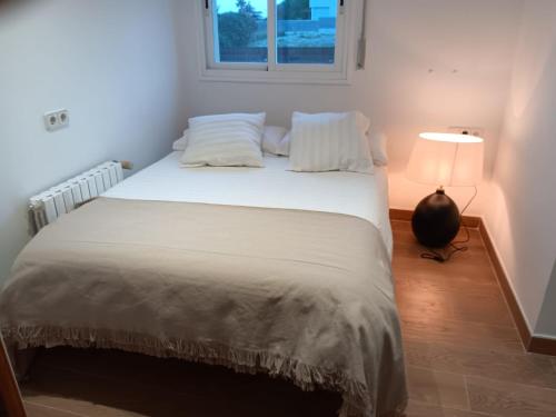 sypialnia z dużym białym łóżkiem z lampką w obiekcie casa santa caterina w mieście Torroella de Montgrí