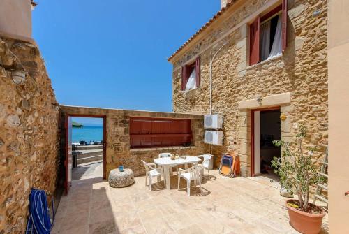 a stone building with a table and chairs on a patio at Waveside Sanctuary - Luxurious Seastone Villa in Avia
