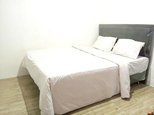 Una cama blanca con sábanas blancas y almohadas. en Saijaan Yogyakarta Mitra RedDoorz, en Kejayan