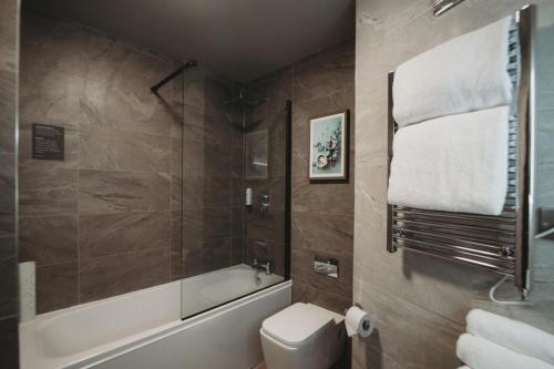 a bathroom with a tub and a toilet and a shower at The Essex Golf & Country Club Hotel in Coggeshall