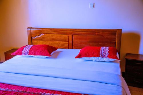 a bed with two red and white pillows on it at Kigali Village Suites in Kigali