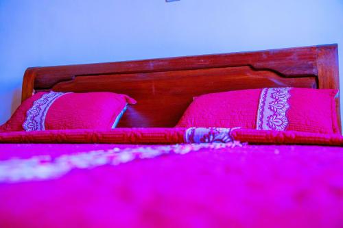 a pink bed with two pink pillows on it at Kigali Village Suites in Kigali