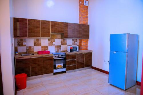 a kitchen with a blue refrigerator and wooden cabinets at Kigali Village Suites in Kigali