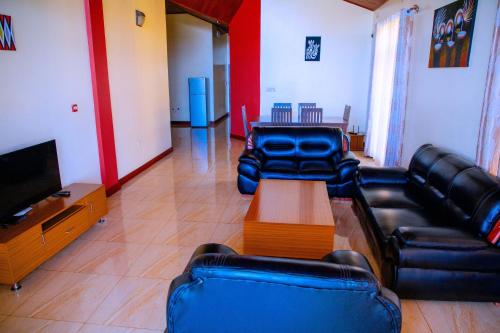 a living room with leather couches and a tv at Kigali Village Suites in Kigali