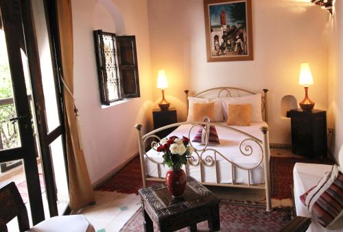 a bedroom with a bed with a vase of flowers on a table at Riad Palmier in Marrakech