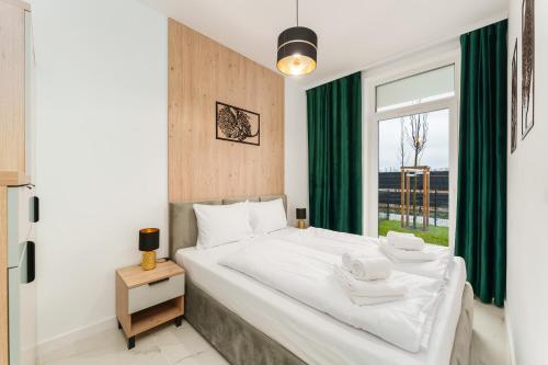 een slaapkamer met een bed met groene gordijnen en een raam bij Apartament Eco Modern II by HolidaySun in Sianozety