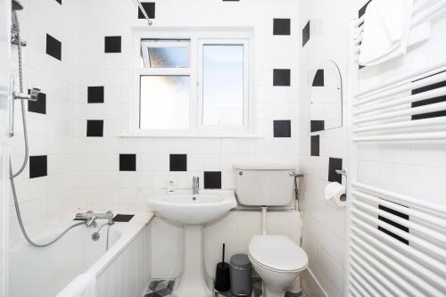 La salle de bains blanche est pourvue de toilettes et d'un lavabo. dans l'établissement Large 4 Bed in Southend, near shops/cafés/beach!, à Southend-on-Sea