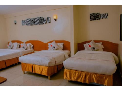 Habitación de hotel con 2 camas con sábanas blancas en Igitego Hotel Remera en Kigali