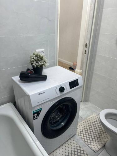 a washing machine in a bathroom next to a toilet at Квартира in Sätbaev