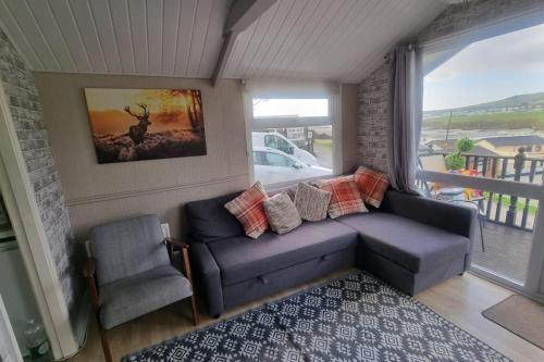 a living room with a couch and a chair and a window at No. 4 Sunny Lodge By The Sea in Aberystwyth