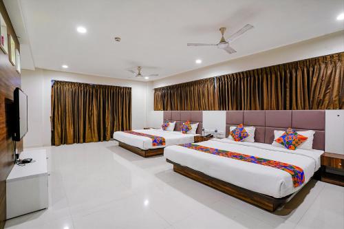 a hotel room with two beds and a flat screen tv at FabHotel La Victoria - Galaxy Circle in Surat