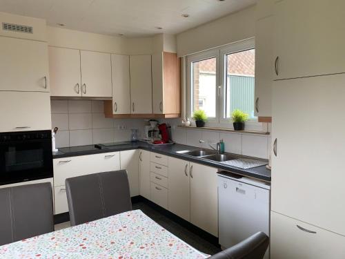 a kitchen with white cabinets and a sink at Vakantie-woning in Sint Kruis