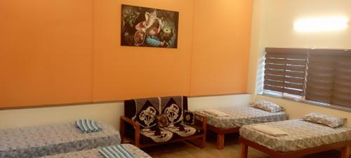 Habitación con 3 camas, 2 sillas y ventana en Arangan Kudil Family Suite, en Tiruchchirāppalli