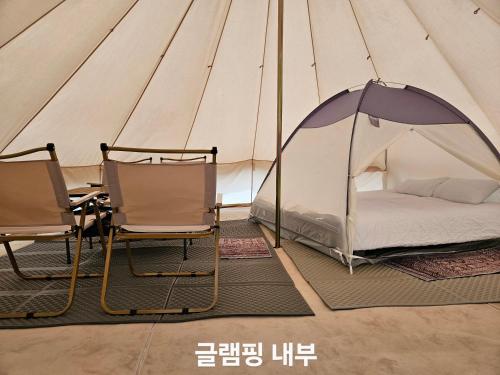 a tent with two chairs and a bed in it at Seoneulgimunhwa in Yeongju