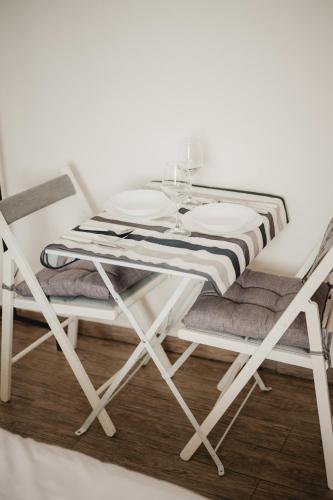 a white dining table and chairs with a glass table and plates at Monolocale Marina in centro storico in Trieste