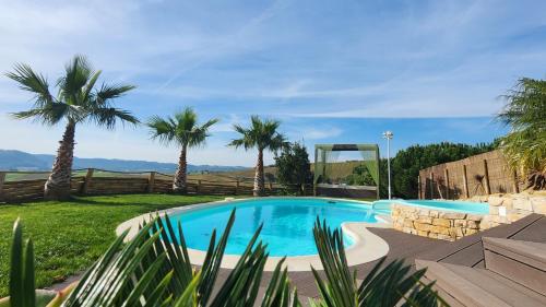 a pool in a yard with palm trees at VILLA ALTUS near Ericeira with swimming pool, jacuzzi and 2 games room in Cambaia