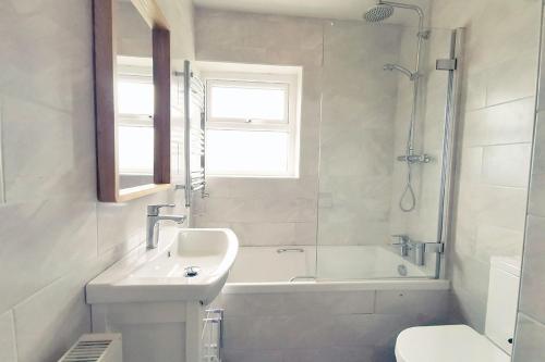 a bathroom with a sink and a tub and a toilet at Sea-Views-3 Bed-Detached Bungalow-Secure Garden-Trearddur Bay in Trearddur