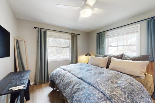 ein Schlafzimmer mit einem Bett und zwei Fenstern in der Unterkunft Romantic River Cabin #3475 in Estes Park
