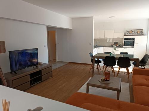 ein Wohnzimmer mit einem Sofa, einem TV und einem Tisch in der Unterkunft Apartman Slatina in Tuzla