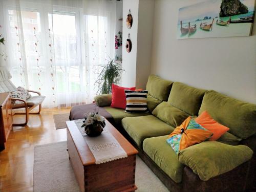 een woonkamer met een groene bank en kleurrijke kussens bij Apartamento de 2 hab. con todo lo necesario. in Gijón