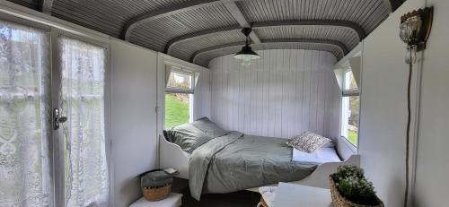 a bedroom with a bed in a room with windows at Petit a Petit - gypsy wagons and Bell tents in the Bourgogne in Saisy